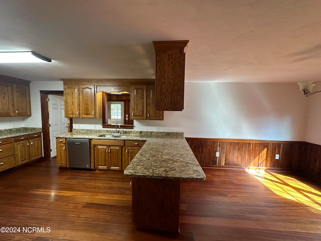 kitchen featuring wood walls, light stone countertops, stainless steel dishwasher, dark hardwood / wood-style floors, and sink