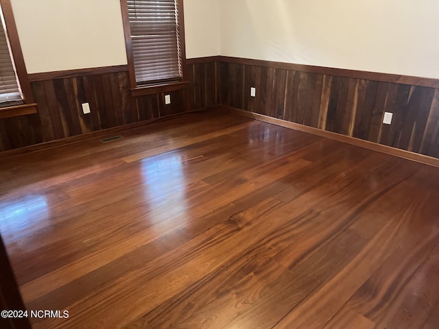 empty room featuring wood walls and hardwood / wood-style flooring