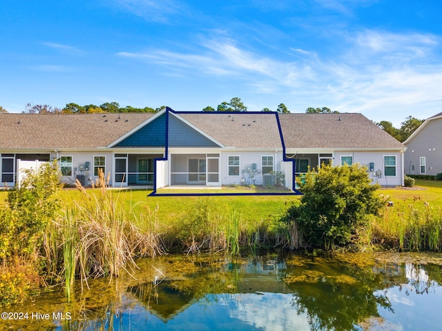 rear view of house featuring a water view, a yard, and a sunroom