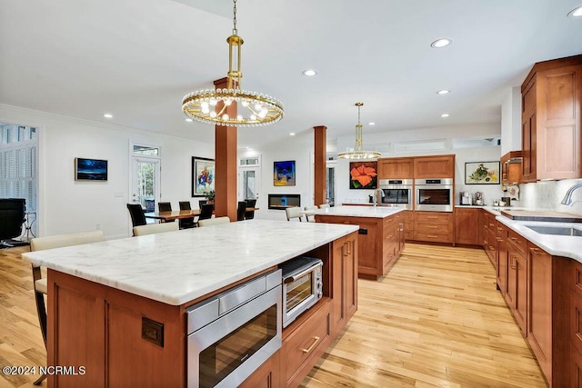 79 Bishop Branch Ln SE, Leland, NC 28451 - kitchen featuring appliances with stainless steel finishes, a center island, a chandelier, a sink, and brown cabinets