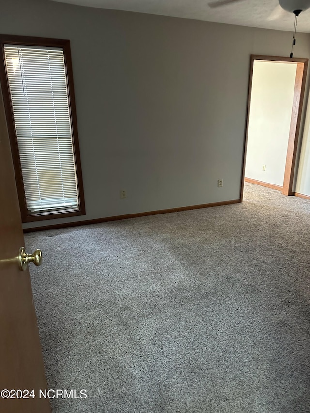 empty room featuring ceiling fan and carpet