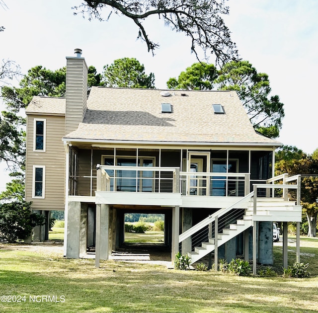 rear view of house featuring a lawn and a sunroom