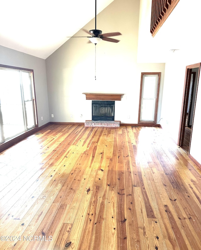 unfurnished living room featuring light hardwood / wood-style floors, high vaulted ceiling, a wealth of natural light, and ceiling fan