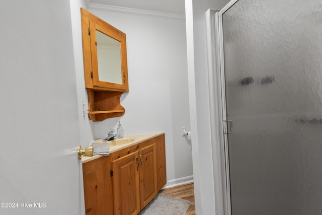 bathroom with vanity, an enclosed shower, hardwood / wood-style floors, and ornamental molding