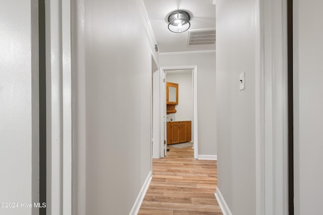 hallway featuring ornamental molding and light hardwood / wood-style floors