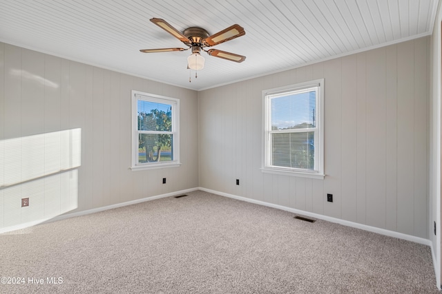 unfurnished room with wood walls, wooden ceiling, ceiling fan, carpet flooring, and crown molding