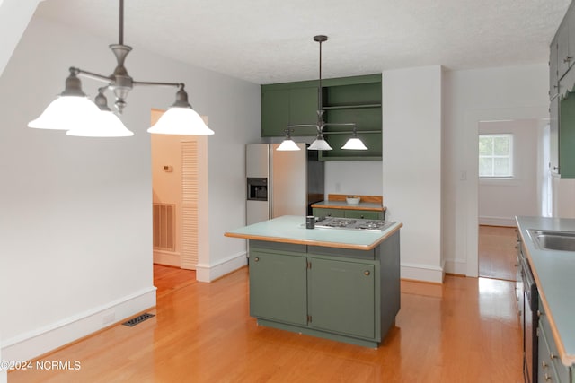 kitchen featuring light wood-type flooring, green cabinets, a textured ceiling, and a center island