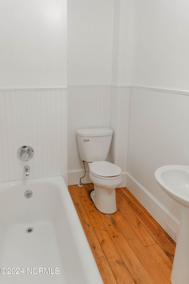 bathroom with wood-type flooring, a bathtub, and toilet