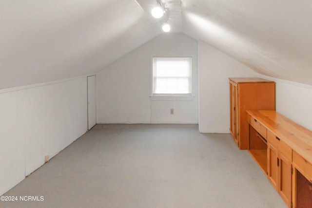 additional living space featuring light colored carpet and lofted ceiling