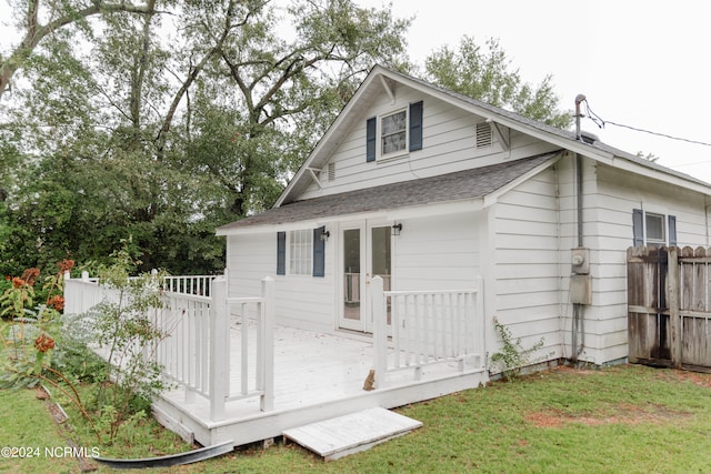 back of property with a wooden deck and a yard