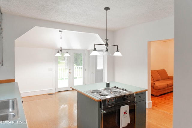 kitchen featuring a textured ceiling, decorative light fixtures, light wood-type flooring, and electric range