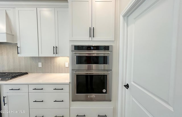 kitchen with appliances with stainless steel finishes, tasteful backsplash, white cabinets, custom exhaust hood, and light stone countertops