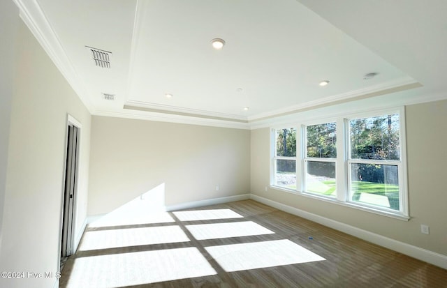 unfurnished room with crown molding, a raised ceiling, and hardwood / wood-style floors