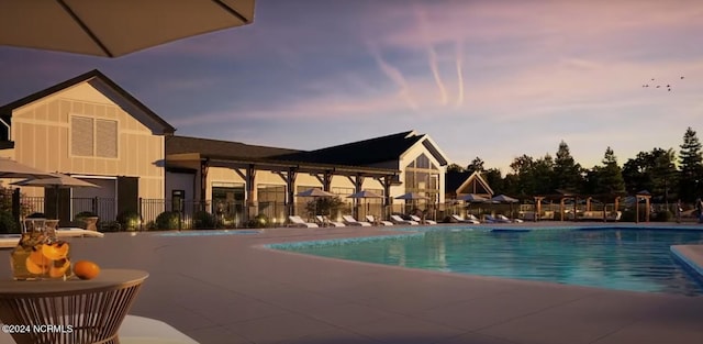 pool at dusk with a patio area