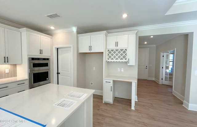 kitchen with white cabinetry, decorative backsplash, crown molding, stainless steel double oven, and light hardwood / wood-style flooring