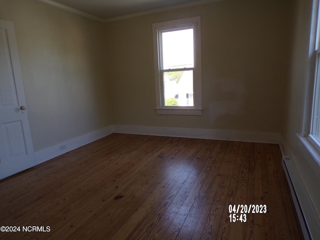 spare room featuring baseboard heating, ornamental molding, and dark hardwood / wood-style floors