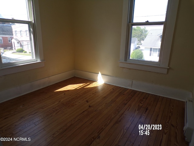 empty room featuring hardwood / wood-style flooring and baseboard heating