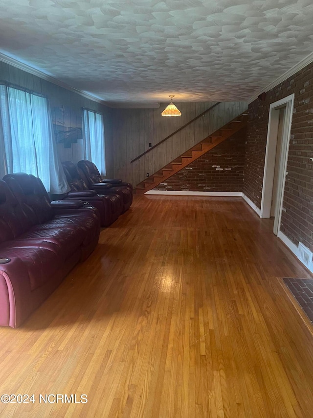 unfurnished living room with wood-type flooring, ornamental molding, and brick wall