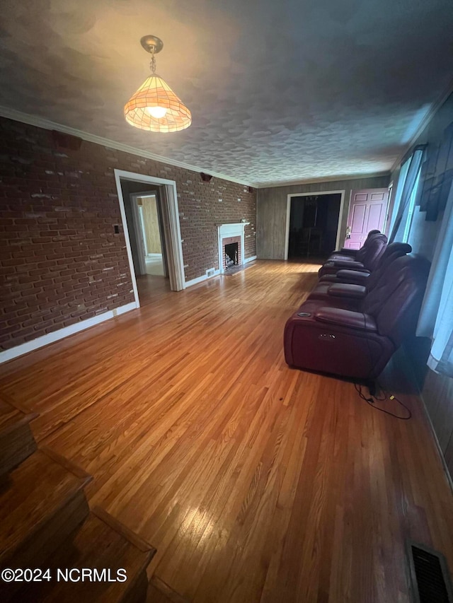 unfurnished living room featuring hardwood / wood-style floors, crown molding, a large fireplace, and brick wall