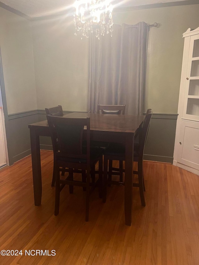 dining space with hardwood / wood-style floors and a chandelier