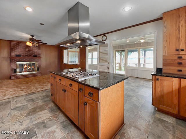 kitchen with island range hood, a kitchen island, ceiling fan, and a brick fireplace