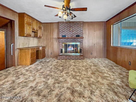 kitchen with ceiling fan, wood walls, carpet flooring, kitchen peninsula, and a brick fireplace