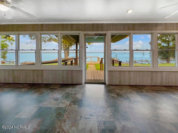 unfurnished sunroom featuring ceiling fan, a water view, and a healthy amount of sunlight