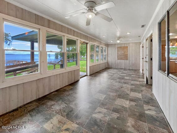 unfurnished sunroom featuring ceiling fan and plenty of natural light