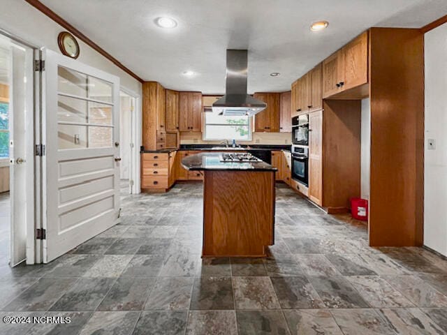 kitchen featuring sink, ornamental molding, a kitchen island, range hood, and stainless steel double oven