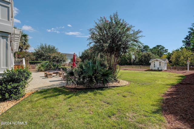 view of yard featuring a storage shed, a patio, fence, and an outdoor structure