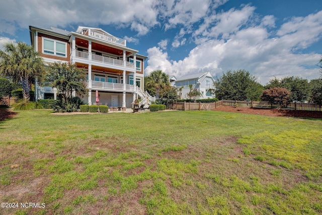 view of yard with stairway, a fenced backyard, and a balcony