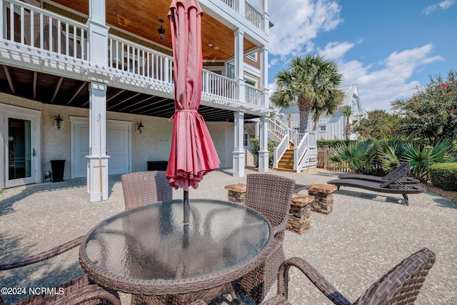 view of patio / terrace featuring outdoor dining area, a wooden deck, and stairway