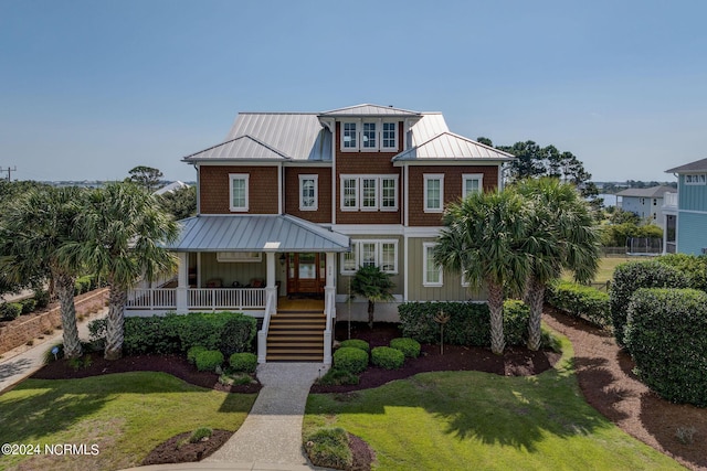 view of front of home with a standing seam roof, a front lawn, a porch, metal roof, and stairs