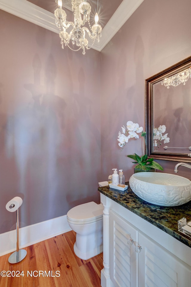 bathroom featuring vanity, wood-type flooring, a chandelier, crown molding, and toilet