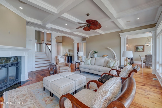 living room featuring beamed ceiling, ornamental molding, coffered ceiling, light wood-type flooring, and ornate columns