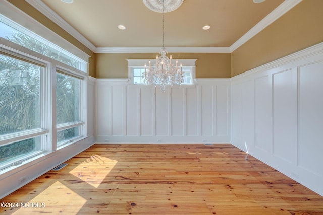 unfurnished dining area featuring a decorative wall, a notable chandelier, and wainscoting
