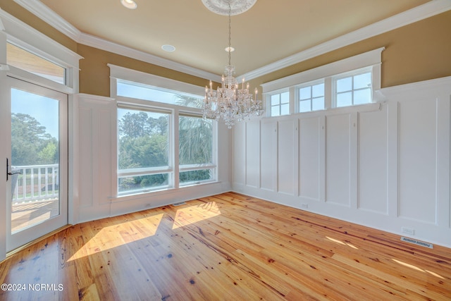 unfurnished dining area with crown molding, light hardwood / wood-style floors, and a chandelier