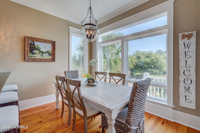 dining area with light wood-type flooring, crown molding, a notable chandelier, and a wealth of natural light