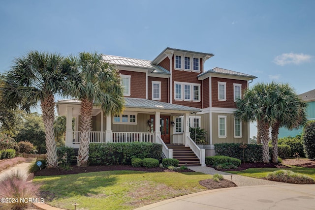view of front of house featuring a porch, a standing seam roof, a front lawn, and metal roof