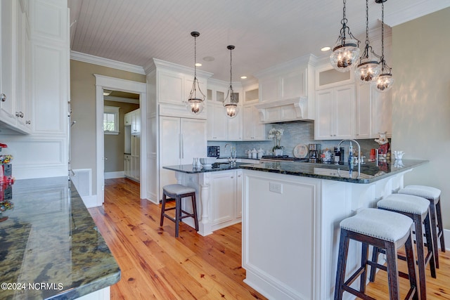 kitchen featuring light hardwood / wood-style floors, white cabinets, a kitchen bar, a kitchen island, and crown molding