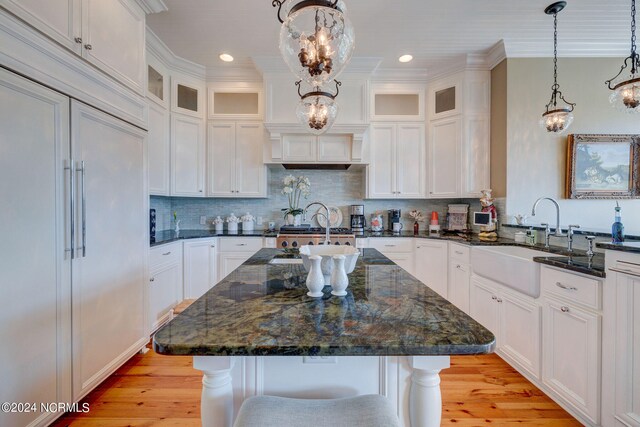 kitchen with light hardwood / wood-style flooring, paneled fridge, and a kitchen island with sink