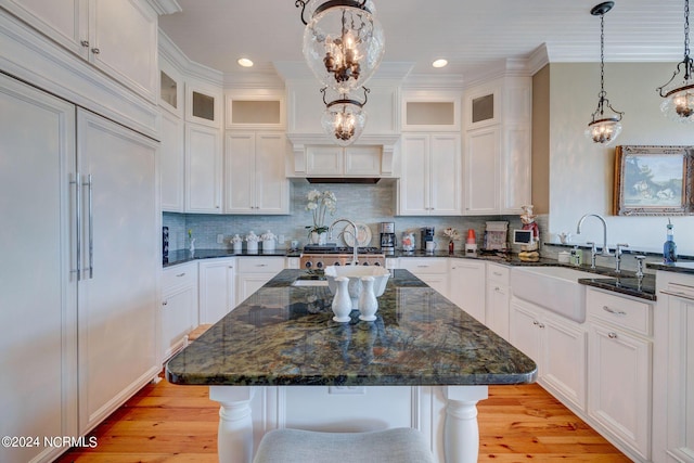 kitchen featuring paneled refrigerator, white cabinetry, a chandelier, and a sink