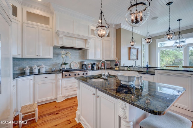 kitchen with stainless steel gas stovetop, white cabinets, and a kitchen island with sink