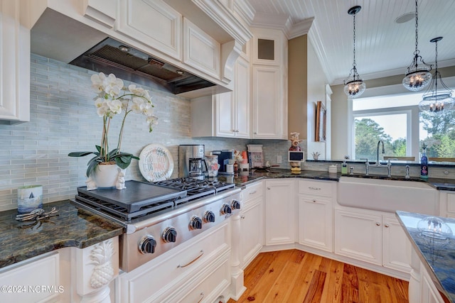 kitchen with a sink, crown molding, stainless steel gas cooktop, white cabinetry, and custom range hood