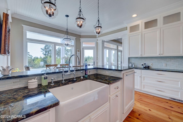 kitchen featuring pendant lighting, sink, white cabinetry, dark stone countertops, and light hardwood / wood-style floors