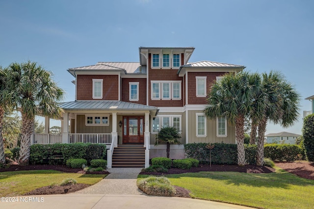 view of front of property featuring a porch, a standing seam roof, a front lawn, and metal roof