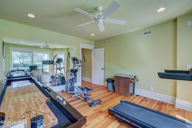 exercise area featuring wood finished floors, visible vents, a ceiling fan, and baseboards