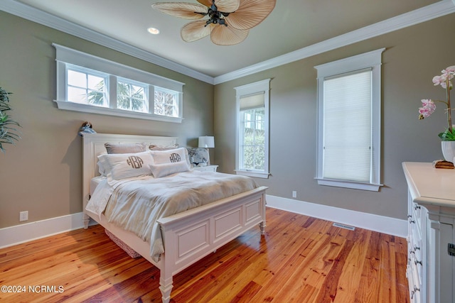 bedroom with light wood-style floors, visible vents, crown molding, and baseboards