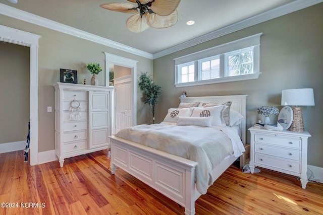 bedroom with ceiling fan, light wood-type flooring, crown molding, and a closet