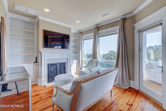 living area with visible vents, a fireplace, light wood-style floors, and ornamental molding